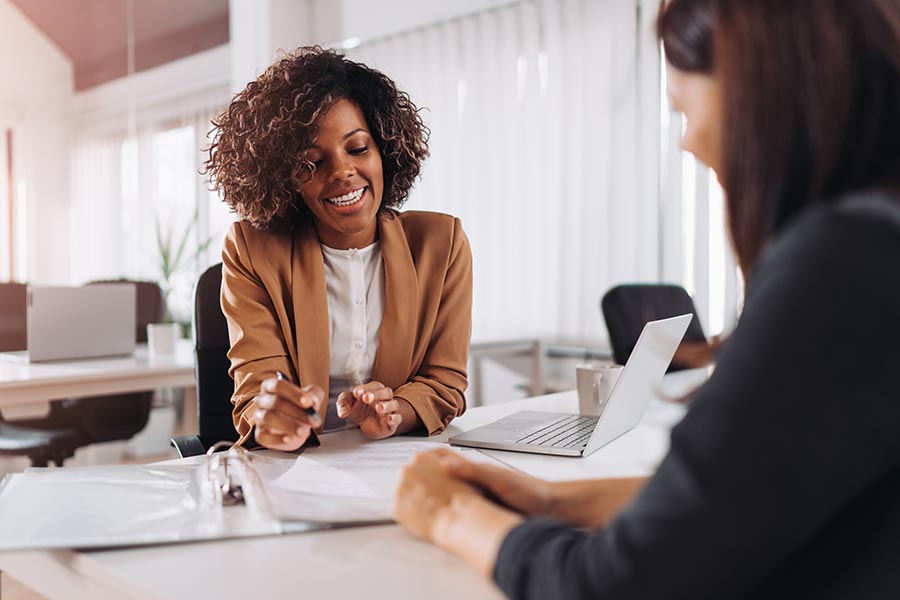 About Our Agency - Smiling Businesswoman Helping Clients at Her Desk